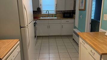A kitchen with white cabinets, a refrigerator, a microwave, and a ceiling fan.