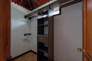 Ein Zimmer mit Holztür, weißer Wand und einem Holzregal mit Kleiderstange.