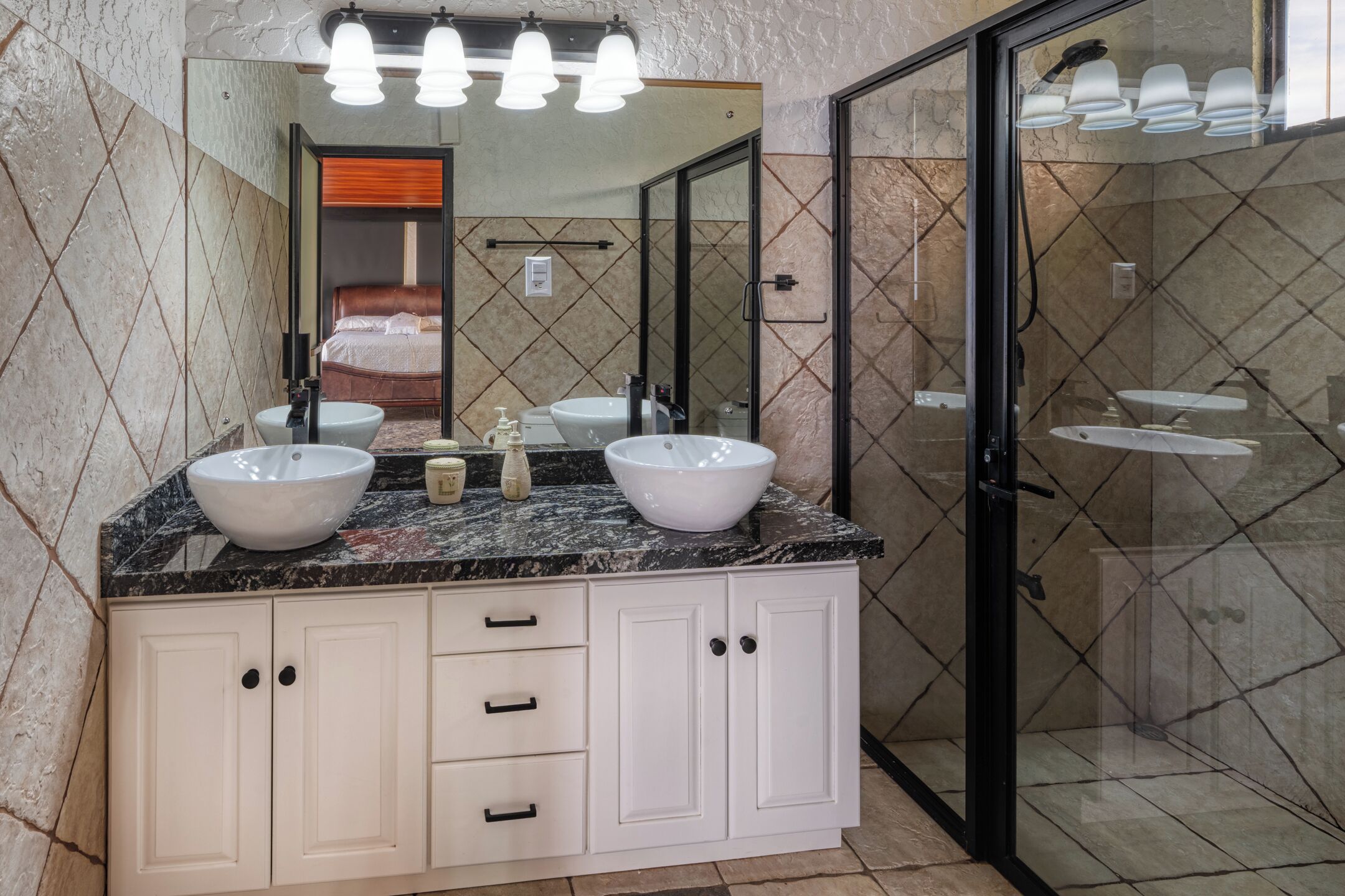 A bathroom with two sinks, a mirror, and a shower area.