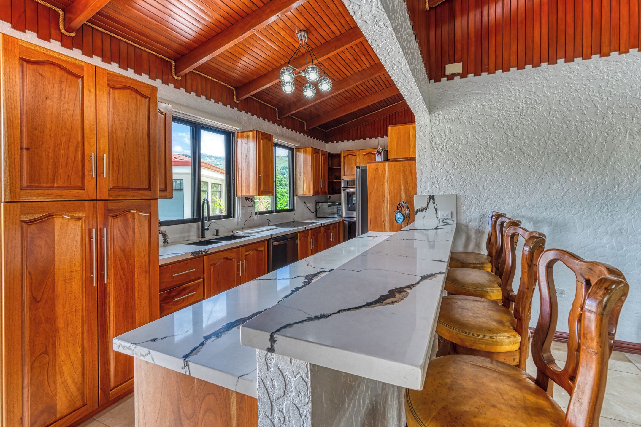 A kitchen with wooden cabinets, a marble countertop, and a built-in oven.