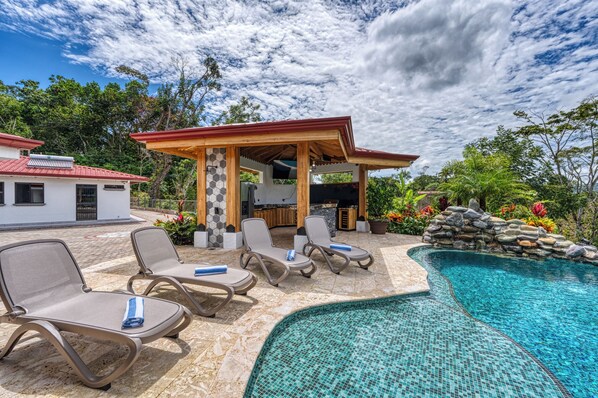 A poolside area with lounge chairs and a covered barbecue area.