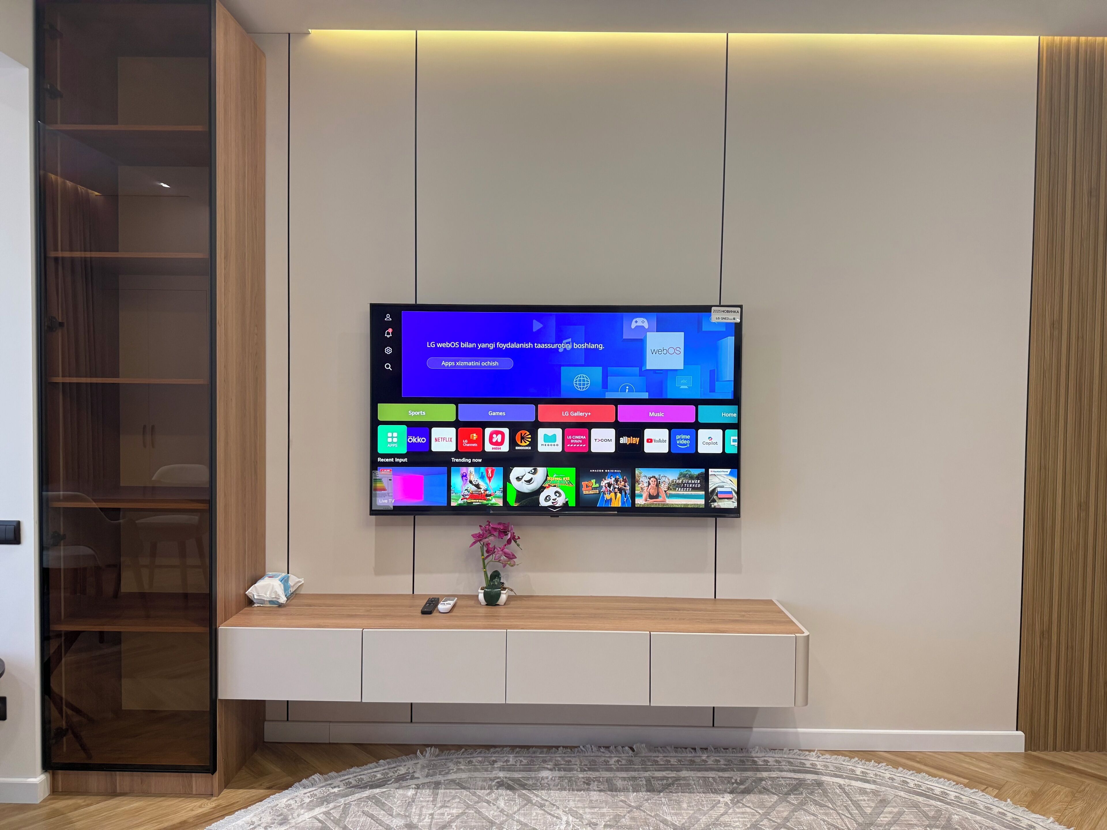 Un téléviseur à écran plat fixé au mur, avec un meuble en bois placé en dessous.