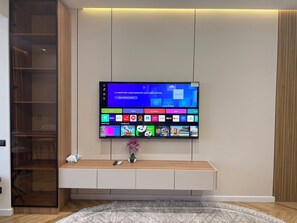 Een flatscreen televisie hangt aan de muur, met een houten kastje eronder.