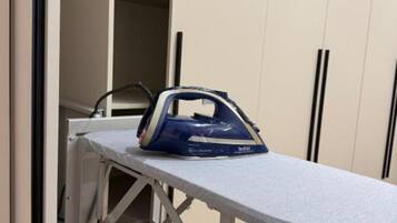 A room with a built-in ironing station and a wardrobe with black handles.