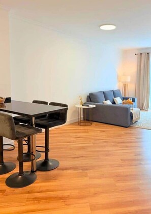 A modern living room with a dining area, a sofa, a lamp, and a small table. - Madeira Sea Escape by Stayguest (Caniço)