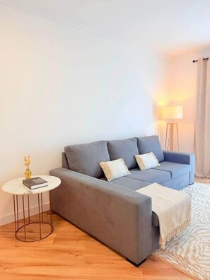 A modern living room with a grey sofa, a small round table, and a floor lamp. - Madeira Sea Escape by Stayguest (Caniço)