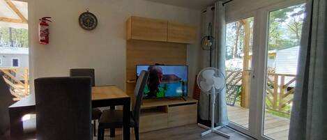 Una sala de estar con una televisión, un ventilador y un extintor en la pared.