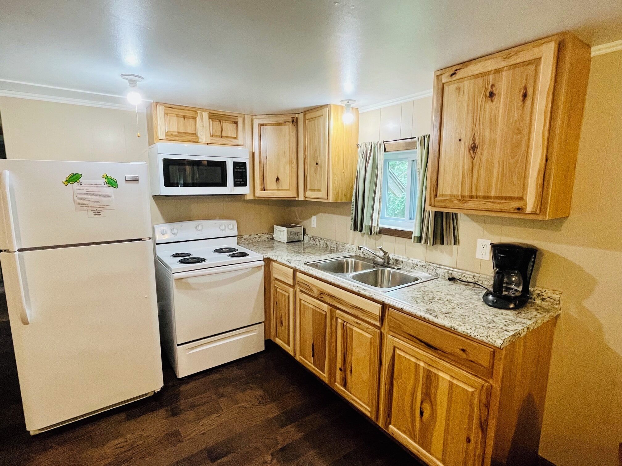 Una cocina compacta con refrigerador, microondas, estufa y armarios de madera.