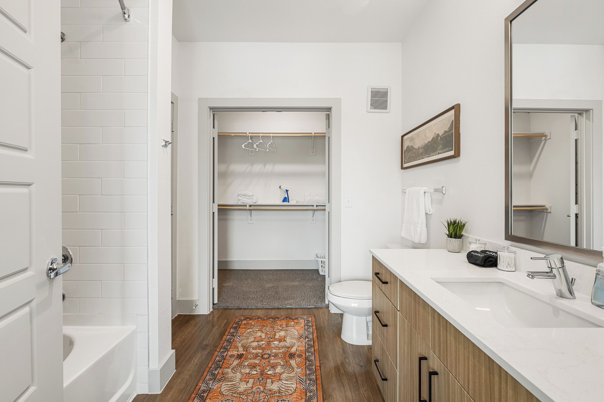 A bathroom with a bathtub, toilet, and a vanity with a mirror.
