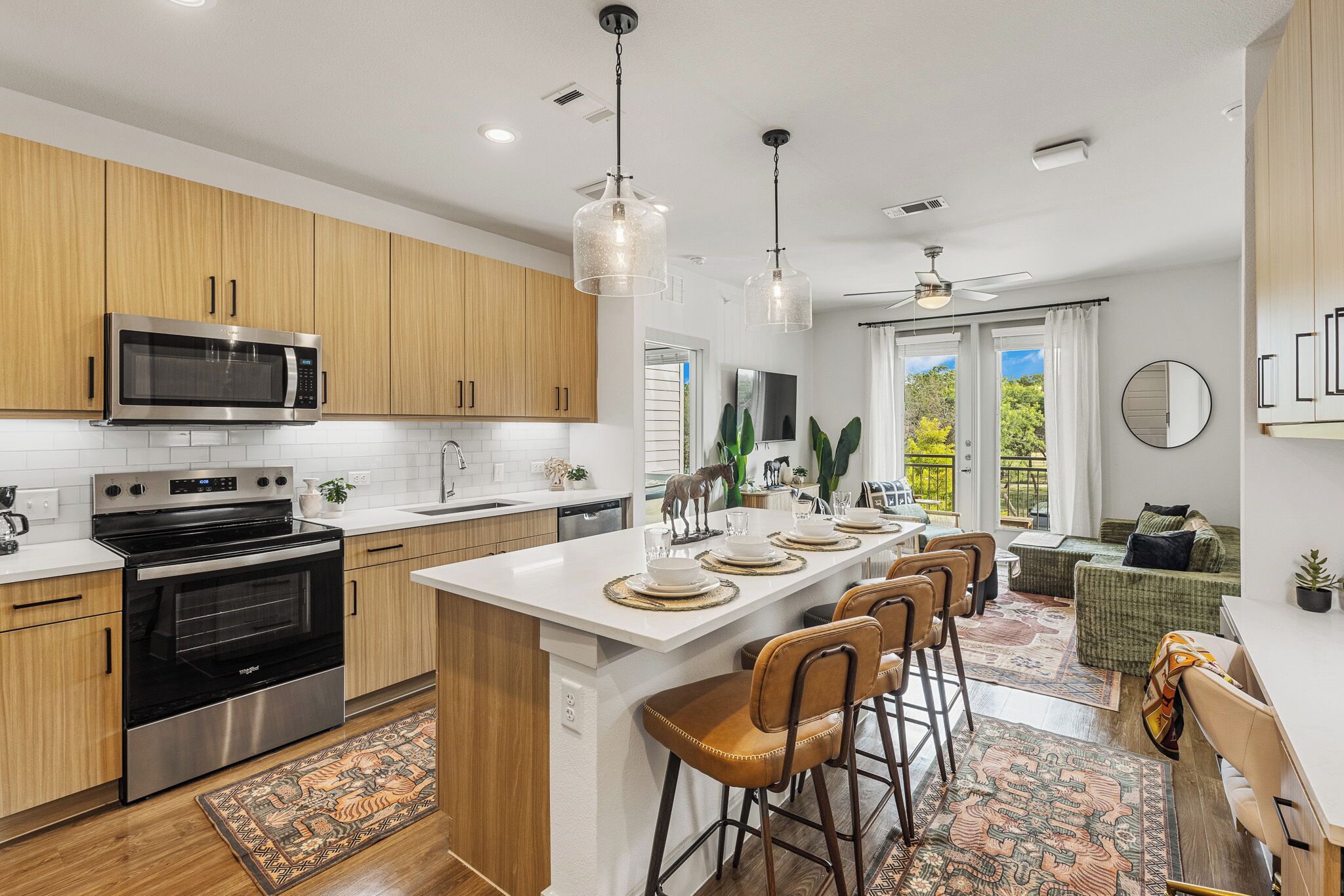 A modern kitchen with stainless steel appliances, wooden cabinets, and a central island with bar stools.