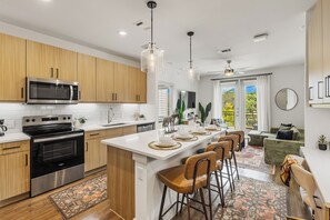 A modern kitchen with stainless steel appliances, wooden cabinets, and a central island with bar stools.