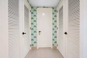 A hallway with a white door, flanked by two white doors with horizontal louvered panels. - Luxury Villa | Casa WED | Bahia Beach PR (Rio Grande)
