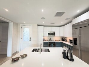 A modern kitchen with a central island, stainless steel appliances, and a walk-in pantry. - Luxury Villa | Casa WED | Bahia Beach PR (Rio Grande)