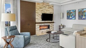 Een moderne woonkamer met een open haard, een flatscreen televisie erboven, een bank, een salontafel en kunstwerken aan de muur.