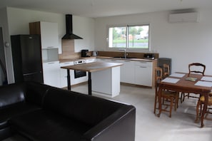 A modern kitchen with a central island, a dining area with a table and chairs, and a black leather sofa. - A charming, comfortable home in the Périgord Noir, near castles and a golf course. (Saint-Germain-de-Belvès)