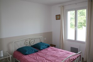 A single-bed room with a metal headboard, a window with curtains, a small bedside table, and a wall-mounted picture. - A charming, comfortable home in the Périgord Noir, near castles and a golf course. (Saint-Germain-de-Belvès)