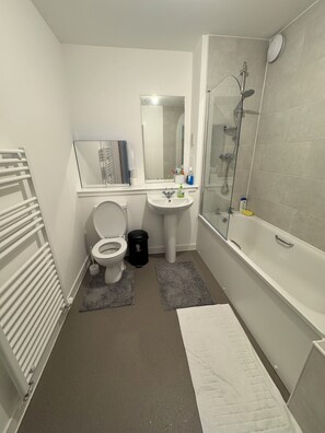 Ein Badezimmer mit Toilette, Waschbecken, Dusche und Spiegel.