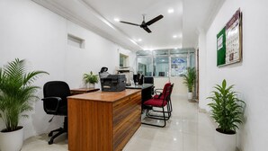 Ein Büro mit Empfangstresen, Stühlen, Deckenventilator und Topfpflanzen.