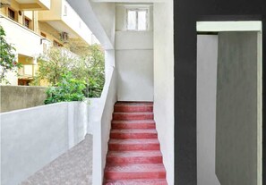 Eine Treppe mit roten, gemusterten Stufen, die zu einer Zwischenebene führt.
