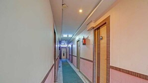 Ein Korridor mit Türen an beiden Seiten, einem an der Wand befestigten Feuerlöscher und einer Deckenleuchte.