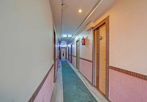 Ein Korridor mit Türen an beiden Seiten, einem an der Wand befestigten Feuerlöscher und einer Deckenleuchte.