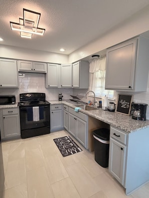 A modern kitchen with white cabinets, a black stove, and a granite countertop.