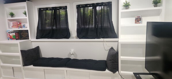 A room with a bed, a TV, and a window with black curtains.