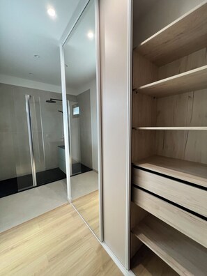 Un baño moderno con cabina de ducha de vidrio, tocador de madera y espejo.