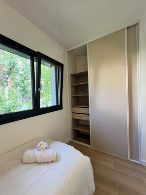 Ein Schlafzimmer mit Bett, Fenster und einem Einbauschrank.