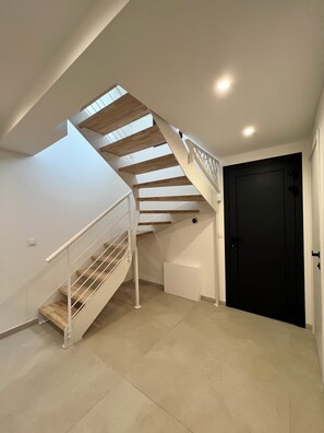 A staircase with a wooden finish and white railings leading to an upper floor. - Villa Nova Annecy | Downtown & Lake | Sleeps 8 (Annecy)