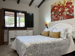 A bedroom with a bed, a dresser, a window, and a painting.