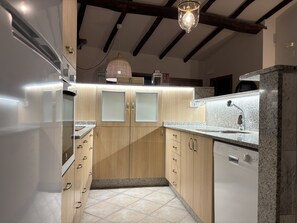 Eine moderne Küche mit Holzschränken, einem eingebauten Geschirrspüler und einer Pendelleuchte.