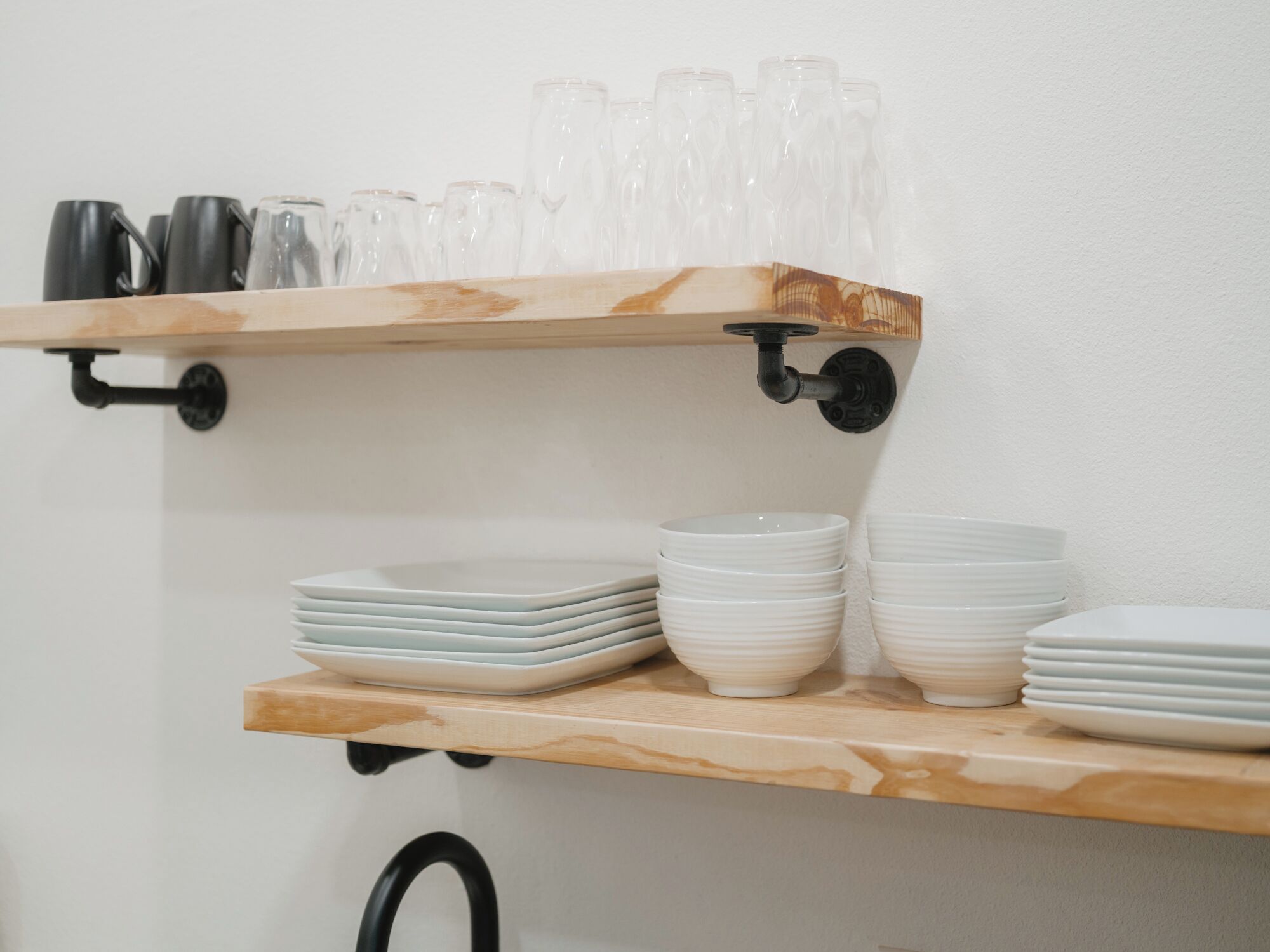 Una estantería de madera con cristalería y platos apilados.