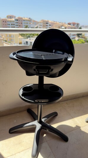 A portable grill on a balcony with a cityscape view in the background. - Sunny Algarve Retreat - Pool & 10 min to beach (Portimão)