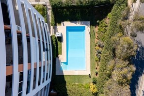 Edifício residencial com piscina e um jardim bem cuidado.