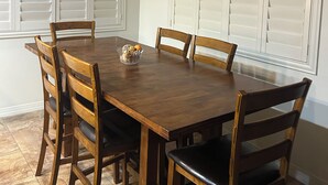 A dining room with a wooden table, six chairs, and a ceiling fan. - Beautiful, furnished single level home Great for travel Nurse/corp. housing 55+ (Mesa)