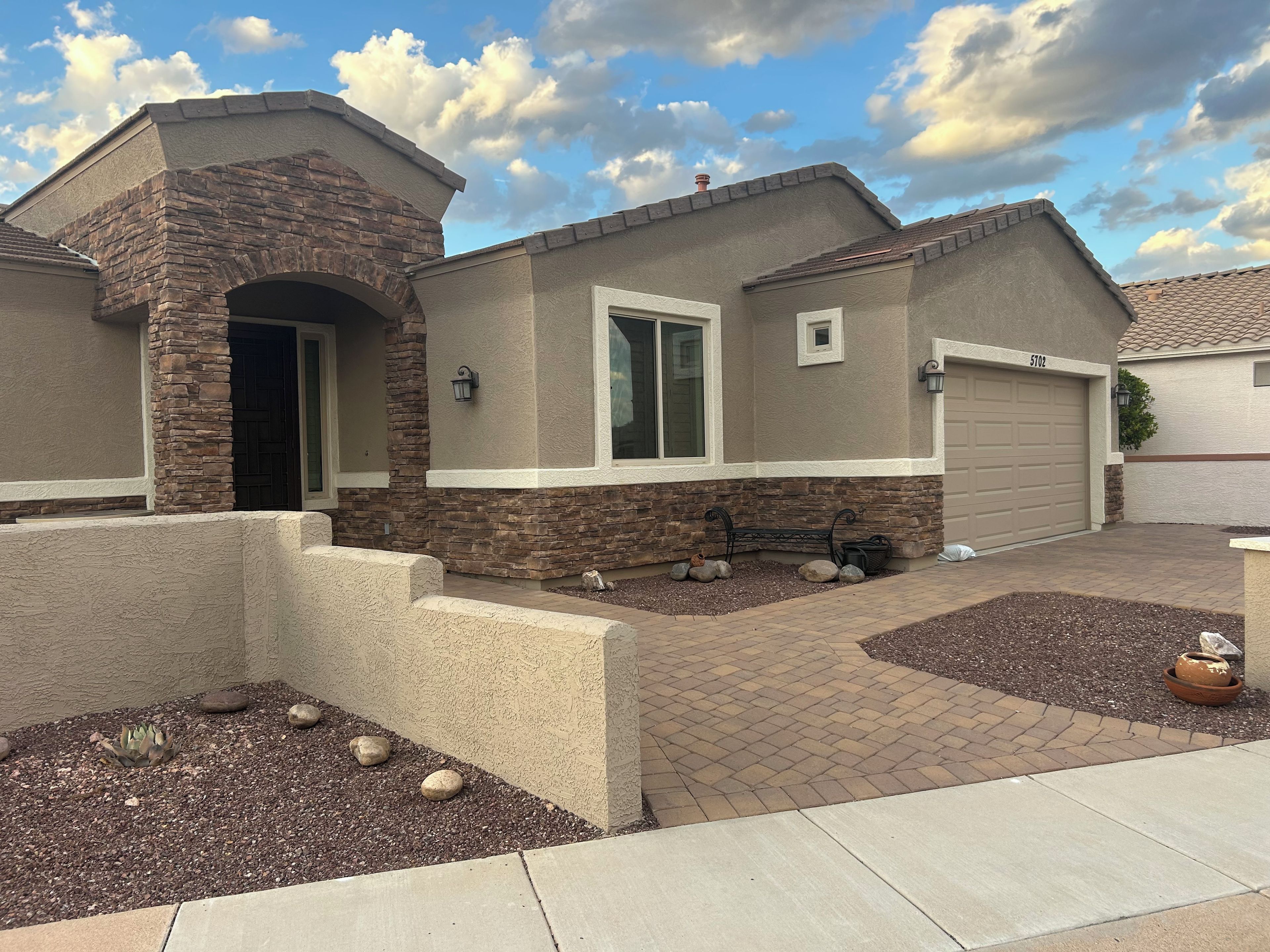 A residential house with a stone facade, a garage, and a landscaped front yard.