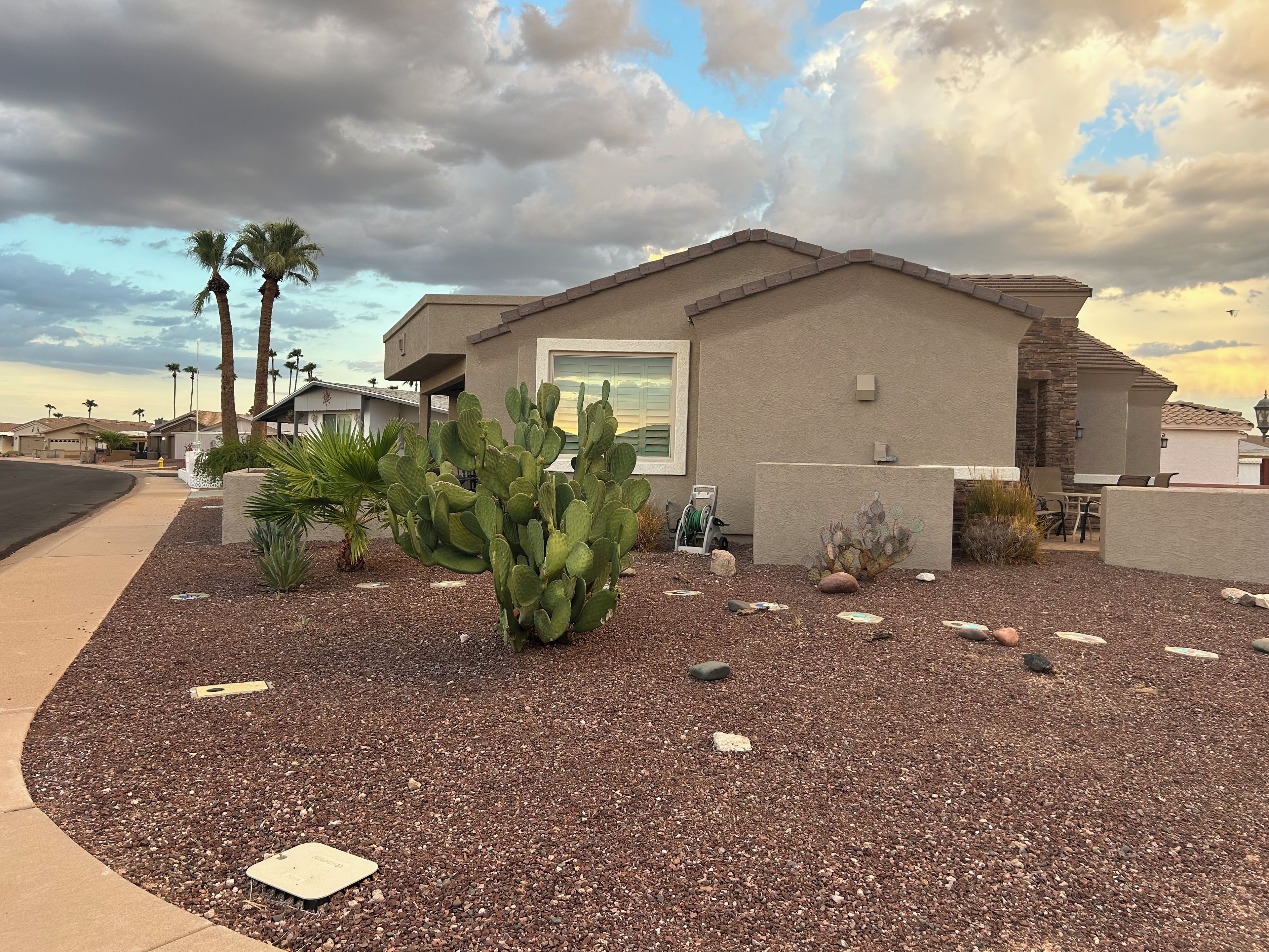 A residential building with a patio area, a cactus, and a stone wall.