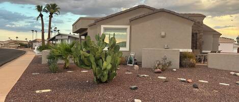A residential building with a patio area, a cactus, and a stone wall.