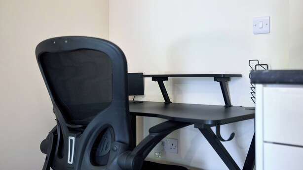 Um espaço de trabalho com cadeira, mesa e tomada na parede.