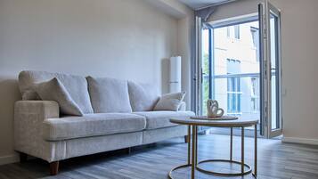 A modern living room with a sofa, a round coffee table, and a large window with an open door.