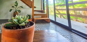 Ein Zimmer mit Blumentopf, einer Holzbank und Blick durch eine Glastür.