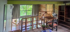 Ein Zimmer mit einer Holztreppe, einem fenster mit Vorhängen und einer Backsteinwand.