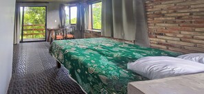 Ein Zimmer mit einem Bett, einem Sessel, einem Tisch und Blick auf Grün.