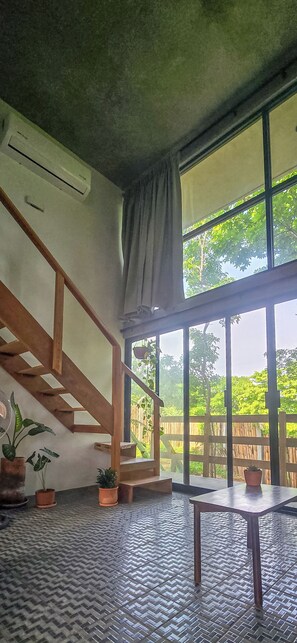 Ein Zimmer mit Treppe, großen Fenstern und Topfpflanzen.