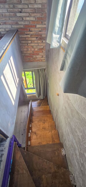 Una escala que condueix a una finestra amb vistes a vegetació.