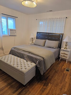 A bedroom with a bed, bedside tables, a lamp, a window, and a ceiling light fixture. - Spacious Ranch 5-bedroom house with parking and garage on no outlet strret (Cincinnati)
