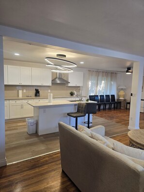 A modern kitchen with white cabinets, a central island, and a dining area with a table and chairs. - Spacious Ranch 5-bedroom house with parking and garage on no outlet strret (Cincinnati)