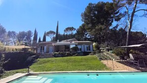 Ein Wohnhaus mit Swimmingpool, ein Haus mit Ziegeldach und einem gepflegten Rasen.