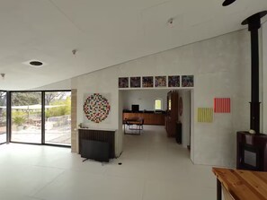 A spacious interior with a large glass door leading to an outdoor area, a modern kitchen with a dining area, and a unique circular wall art piece. - Villa Cézanne Panorama, Downtown Within Walking Distance (Aix-en-Provence)